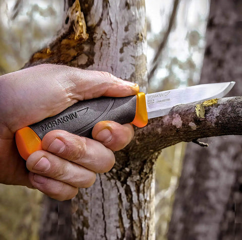 Hand holding heavy duty outdoor knife with 4.1-inch stainless steel blade and orange handle for bushcraft, camping, hunting, fishing, survival readiness