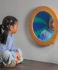 Light Up 3D Circular Infinity Mirror With Color Changing Tunnel Lighting For Calming Sensory Stimulation In Classrooms And Clinics Multicolor Visual Illusion That Transforms Any Space with child observing reflections indoors.