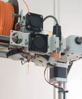 3D printer setup with NEMA 23 motor bracket and filament spool. Close-up of extruder showcasing wiring and mechanical components.