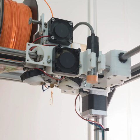 3D printer setup with NEMA 23 motor bracket and filament spool. Close-up of extruder showcasing wiring and mechanical components.