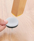Holding a brown nylon furniture glide pad with steel pin for round chair legs, part of 40 Pack Brown Nylon Furniture Glide Pads With Steel Pins For Round Chair Legs Floor Protectors That Reduce Noise And Protect Hardwood Tile Laminate Floors At Home Office Kitchen.