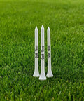 Three white 83mm premium bamboo golf tees standing on grass, part of the Premium Bamboo Golf Tees 83mm Set With Vintage Flip Top Case For Men.