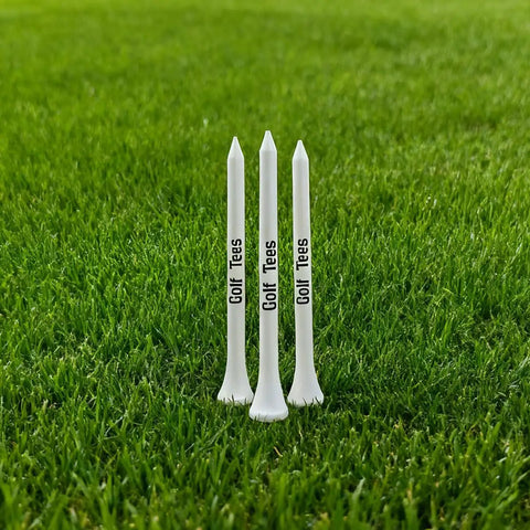 Three white 83mm premium bamboo golf tees standing on grass, part of the Premium Bamboo Golf Tees 83mm Set With Vintage Flip Top Case For Men.