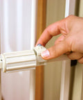 Hand adjusting the pressure mount on a No Drill Pressure Mount Metal Dog Gate for Doorways and Hallways, showing lock detail.