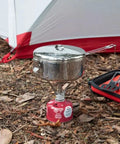 Beefy Stainless Steel Stowaway Camping Pot 475 mL with locking lid on portable stove next to a tent in forest setting