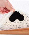 Black heart-shaped non-slip rug pad being placed under rug, 4 Pack Heart Shape Non Slip Rug Pads For Hardwood Floors And Tiles