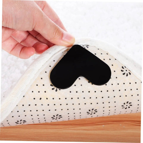 Black heart-shaped non-slip rug pad being placed under rug, 4 Pack Heart Shape Non Slip Rug Pads For Hardwood Floors And Tiles