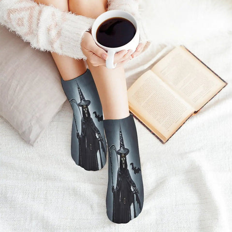 Person wearing witch-themed socks while holding coffee on bed