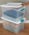 Super Tight Fit 64 Quart Clear Plastic Storage Bins 72 Pack With Snappy Hinged Lids holding neatly folded blankets.
