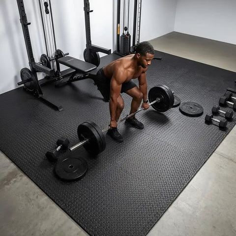 Interlocking 12 Tile Exercise Mat Set For Your Home Gym Setup With 24 By 24 Inch EVA Foam Flooring Puzzle Mats For Safe Workout Area And Equipment Protection Black shown in a gym with weights.