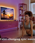 Woman doing yoga in a living room with a 12.5ft RGB LED Backlight Strip for 40 to 55 inch TVs, Bluetooth App Control atmosphere.