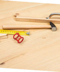 Woodworking tools and accessories on a wooden workbench, including a hammer, measuring tape, and handle