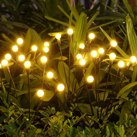 Four Pack Solar Garden Path Lights With 8 LED Firefly Glow Waterproof Outdoor Yard Decor illuminating plants at night