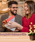 Couple exchanging gifts with Crochet Lily of the Valley Lamp in foreground, cozy home setting, perfect for bedside decor.