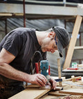 Woodworker using machine for precision cut, focused DIY project environment