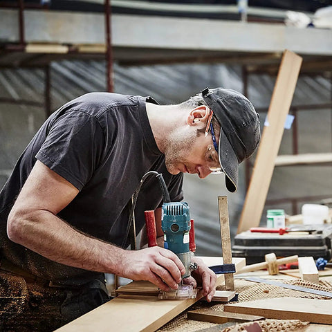 Woodworker using machine for precision cut, focused DIY project environment