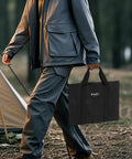Person carrying tote bag with Collapsible 23 Inch Wood Burning Fire Pit For Camping And Patio near a tent