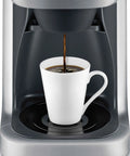 Grind Control Coffee Maker With Built In Grinder, Brushed Stainless Steel, brewing coffee into a white mug, front view