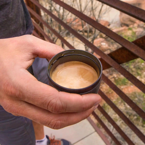 Person holding freshly brewed espresso in a cup from Minipresso GR Portable Espresso Machine For Ground Coffee outdoors
