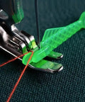 Green fish-type needle threader in use, threading a needle on a sewing machine. Five Piece Fish Type Needle Threaders for Sewing Machines and Hand Sewing.