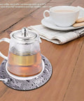 Smart Usb Coffee Mug Warmer And Electric Beverage Heater For Desk Use keeps a tea pot warm on a wooden table, safe up to 80°C.
