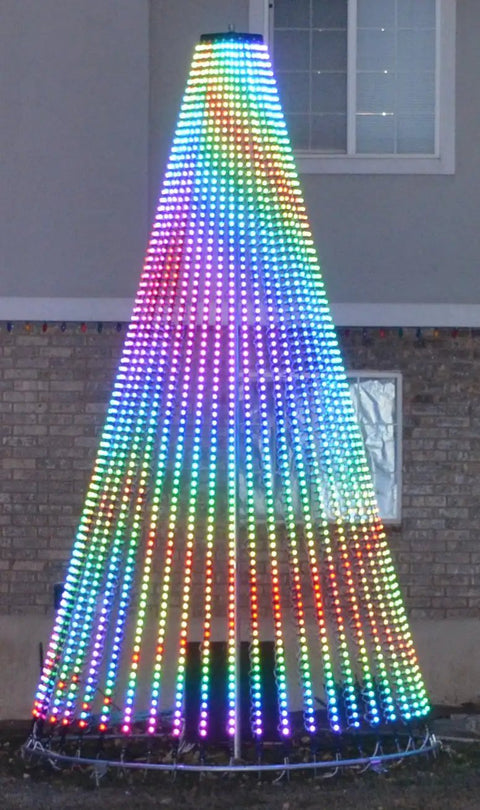 Colorful LED light display in a conical Christmas tree shape illuminated at night in a backyard.