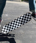 Skateboard mid-air with checkered Ultra Sticky 9 By 33 Grip Tape For Longboards, Cruisers And Scooters, Non Slip Griptape.