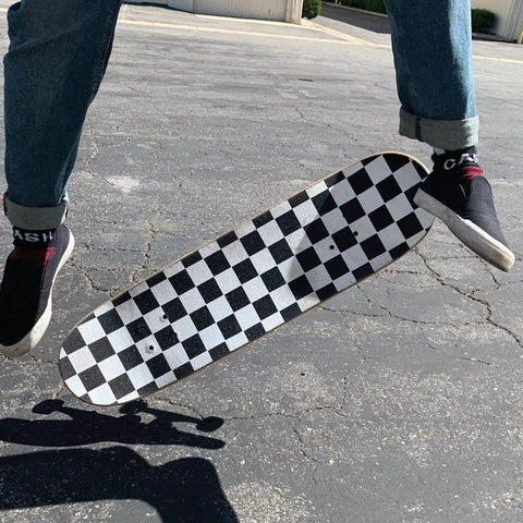 Skateboard mid-air with checkered Ultra Sticky 9 By 33 Grip Tape For Longboards, Cruisers And Scooters, Non Slip Griptape.