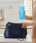 Person holding collapsible soft flask water bottle with ergonomic easy squeeze, ideal for on-the-go hydration, in a kitchen setting.