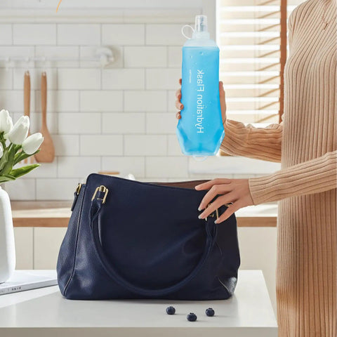 Person holding collapsible soft flask water bottle with ergonomic easy squeeze, ideal for on-the-go hydration, in a kitchen setting.