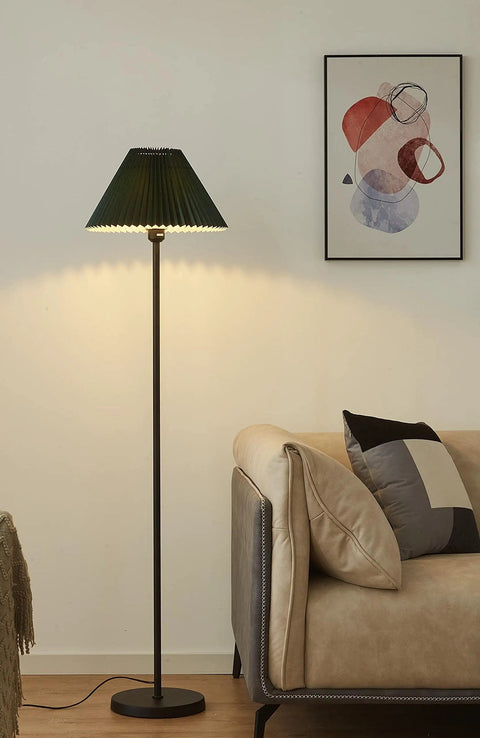 Must Have Black Pole Floor Lamp With Adjustable Height And Dark Green Shade, Metal Base, standing next to a beige armchair.