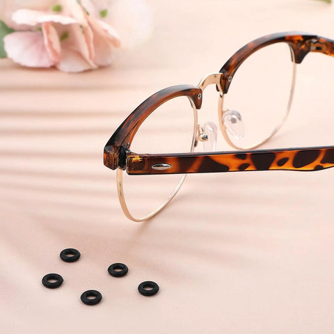 Glasses Repair Kit With Hinge Tighteners, Frame Grips And Silicone Rings, Includes 3 Pairs Of Tighteners And 2 Screwdrivers For Quick Eyewear Fixes On The Go; close-up of eyeglass frame with silicone rings on table.