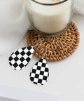 Black And White Checkerboard Teardrop Leather Earrings For Women, Faux PVC Silver Plated Hooks on a woven placemat.