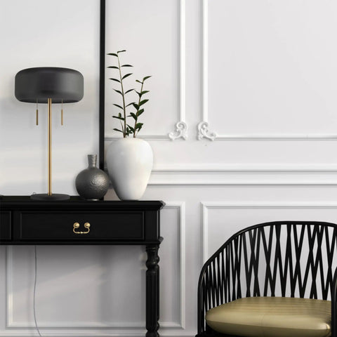 Modern black table lamp on desk with sleek design, near black chair in stylish home office.