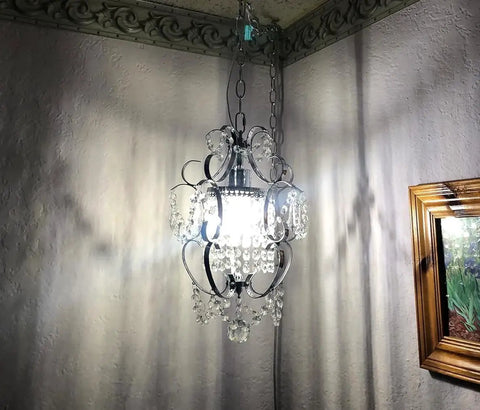 Plug In Chrome Crystal Chandelier With 14.3 Ft Cord And On Off Switch, hanging light fixture illuminated in corner.