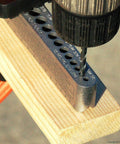 Universal V-Drill Guide for perpendicular hole drilling on flat round and square materials, shown with drill bit in use