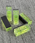 Top Tier 5 Piece Set Of Mini Magnetic Bubble Levels stacked on fabric, featuring green acrylic shell and adhesive backs.
