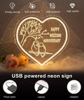 Heart-shaped LED sign with glowing bird design and 'Happy Wedding Anniversary' text, powered by USB, with roses below.