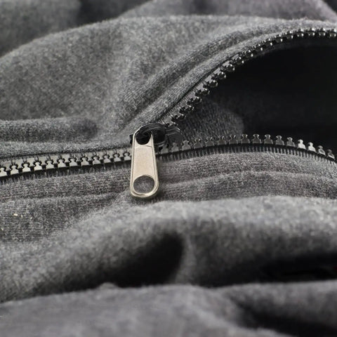 Close-up of a zipper on a gray fabric demonstrating the Six Piece Universal Zipper Repair Kit For Quick Fixes On Clothes Bags And Gear Includes Sliders Top And Bottom Stops Zipper Teeth Design Easy DIY Repair Kit For Fast Zipper Fixes Durable All In One product in use.