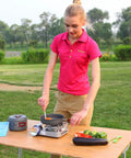 Woman using durable camping cookware set with nonstick hard anodized aluminum pots and pans mess kit for outdoor cooking