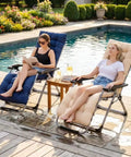 Two women lounging on 61 Inch Lounger Cushion For Outdoor Patio Zero Gravity Chairs Navy Blue Thick And Comfy near a pool.