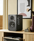 Powered Bookshelf Speakers With Wireless 100W RMS Bluetooth And EARC placed on a wooden shelf, showcasing carbon fiber 4-inch woofer.