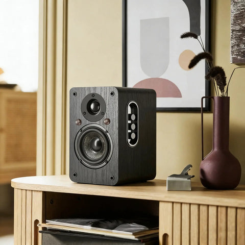 Powered Bookshelf Speakers With Wireless 100W RMS Bluetooth And EARC placed on a wooden shelf, showcasing carbon fiber 4-inch woofer.