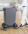 Heavy Duty Trash Can Dolly Featuring Slick 4 Way Swivel Casters Fitting 16 And 23 Gallon Bins Built Tough For No Sweat Waste Moving Up To 200 Lbs Capacity in a gym setting.