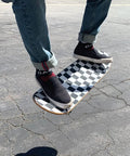 Ultra Sticky 9 By 33 Grip Tape For Longboards, Cruisers And Scooters on a skateboard with checkerboard pattern in use outdoors.