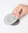 Premium Soft Silicone Bathtub Drain Stopper With Super Strong Suction Cup being removed from a drain for baby bath times.