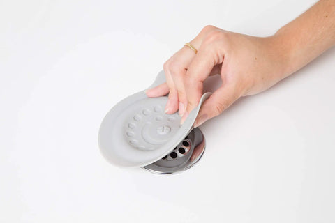 Premium Soft Silicone Bathtub Drain Stopper With Super Strong Suction Cup being removed from a drain for baby bath times.