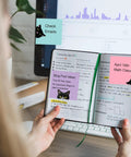 Person holding notebook with Nine Pad Cat Themed Sticky Notes Set In Pink With Super Adhesive Self Stick Notes on pages, monitor in background
