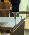 Close-up of drill using a stainless steel self-tapping screw in wood for home repair and furniture making.