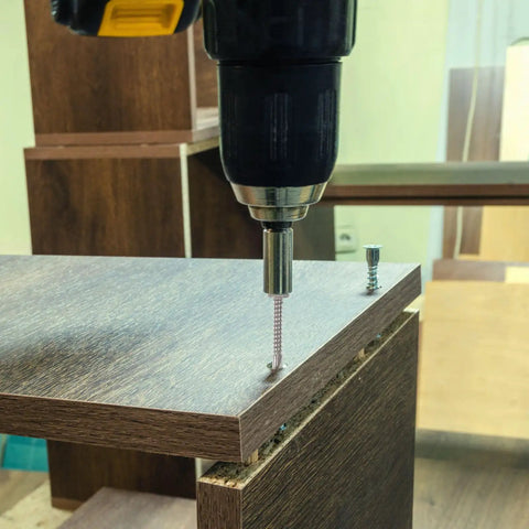 Close-up of drill using a stainless steel self-tapping screw in wood for home repair and furniture making.